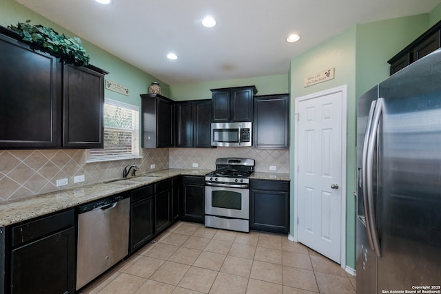 kitchen featuring light tile patterned flooring, sink, decorative backsplash, light stone counters, and stainless steel appliances