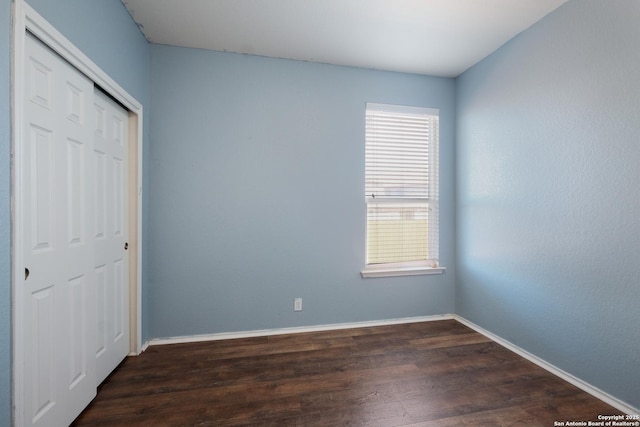 unfurnished bedroom with dark wood-type flooring and a closet