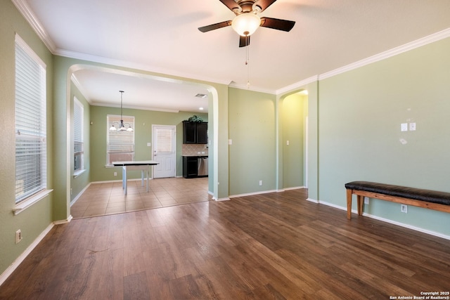 interior space featuring dark hardwood / wood-style flooring, ceiling fan with notable chandelier, and crown molding