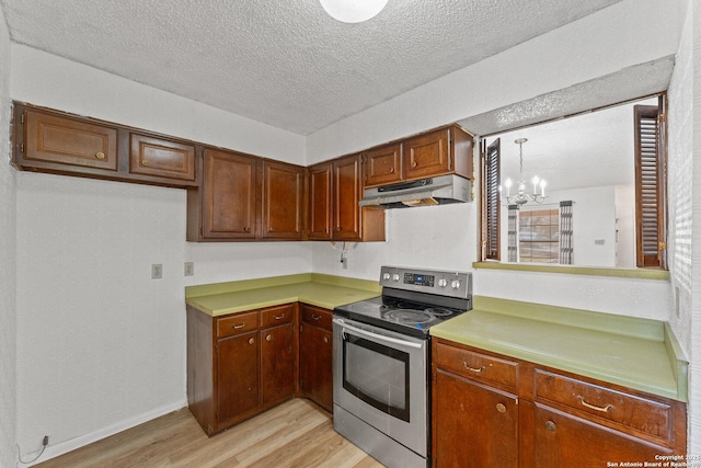 kitchen with stainless steel electric range oven, a textured ceiling, hanging light fixtures, a notable chandelier, and light hardwood / wood-style floors