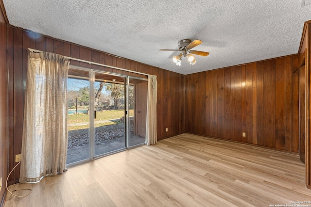 spare room featuring wood walls, ceiling fan, and light hardwood / wood-style flooring