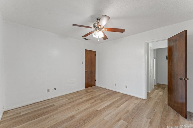 spare room with ceiling fan, a textured ceiling, and light wood-type flooring