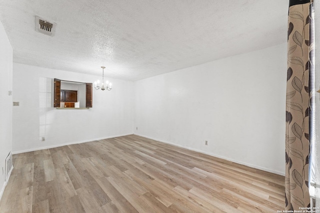 unfurnished room featuring a chandelier, light hardwood / wood-style floors, and a textured ceiling