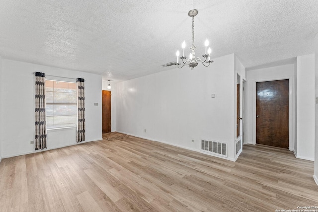 unfurnished room with a chandelier, light hardwood / wood-style flooring, and a textured ceiling