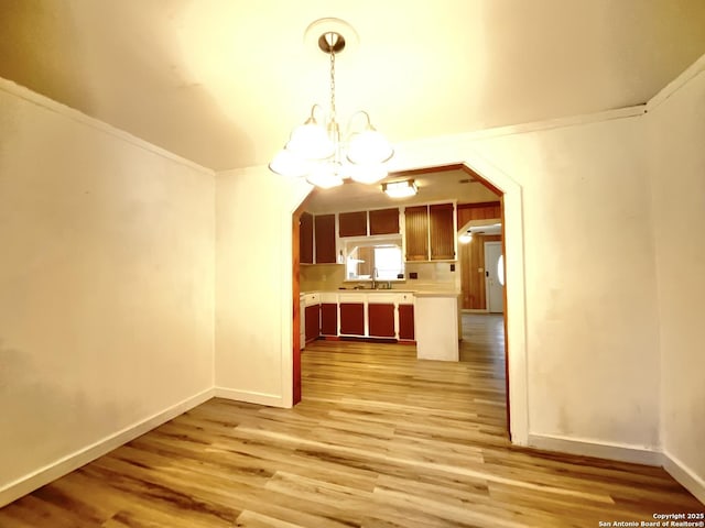 interior space with crown molding, sink, light hardwood / wood-style flooring, and a notable chandelier