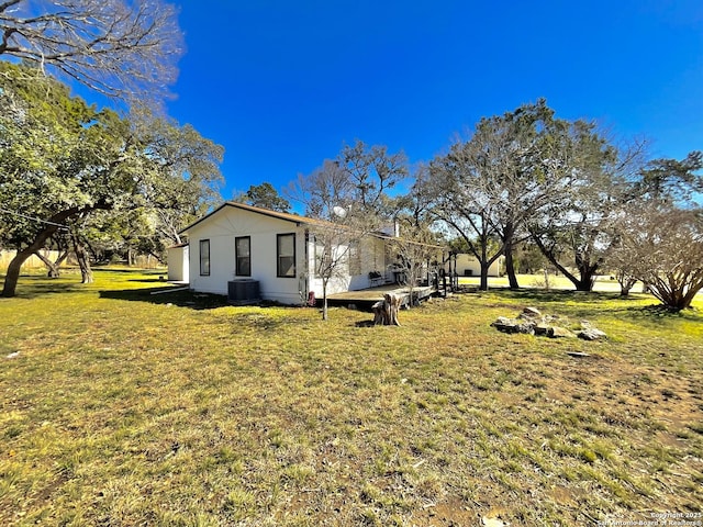 view of side of home with central AC and a lawn