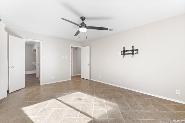 unfurnished bedroom featuring a walk in closet, light tile patterned floors, and ceiling fan