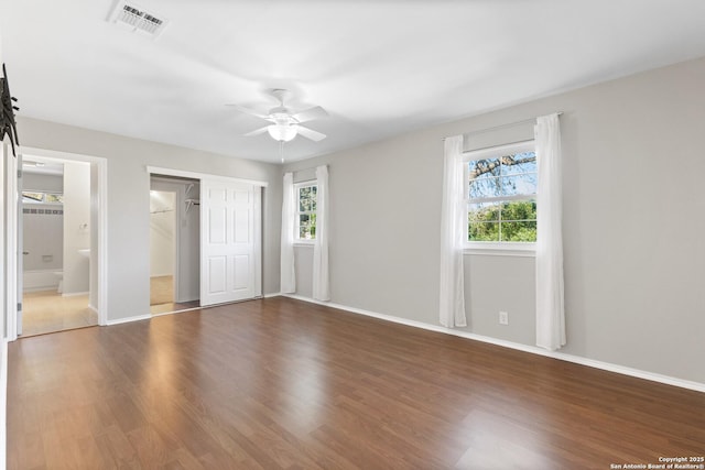 unfurnished bedroom featuring multiple windows, dark wood-type flooring, a closet, and ceiling fan