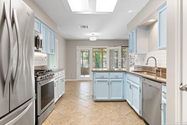 kitchen with light tile patterned flooring, sink, kitchen peninsula, stainless steel appliances, and blue cabinetry