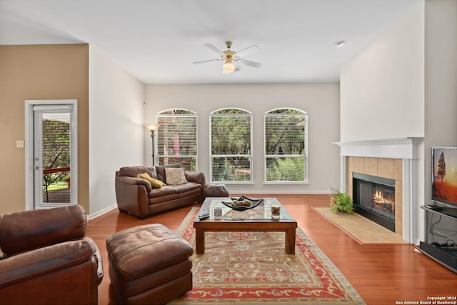living room featuring ceiling fan, a fireplace, and light hardwood / wood-style floors