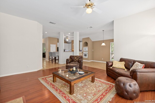 living room featuring wood-type flooring, vaulted ceiling, and ceiling fan