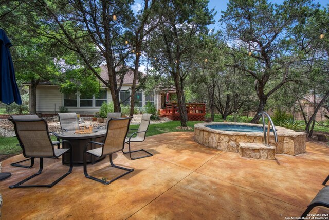 view of patio / terrace with a fire pit, a deck, and an in ground hot tub