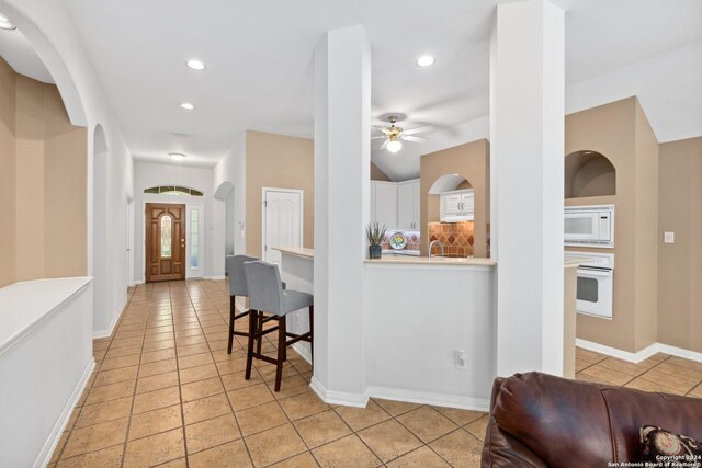 kitchen with white appliances, light tile patterned floors, and white cabinets
