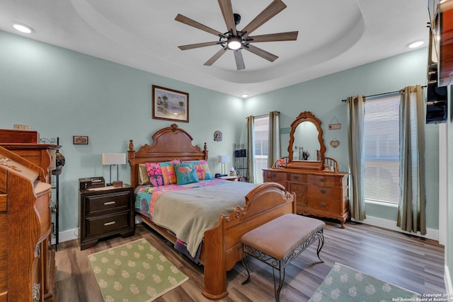 bedroom featuring hardwood / wood-style floors, ceiling fan, and a tray ceiling