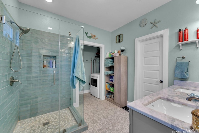 bathroom with a shower with door, vanity, and washer / dryer