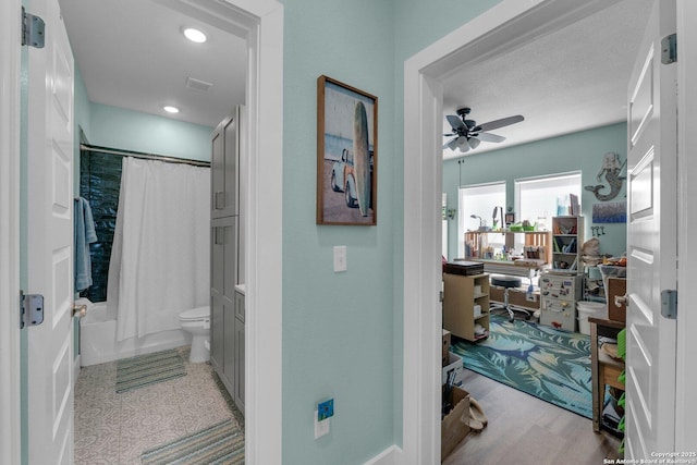 bathroom with hardwood / wood-style flooring, shower / bath combination with curtain, ceiling fan, and toilet