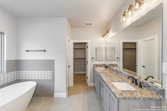 bathroom featuring a bathing tub, vanity, and tile patterned floors