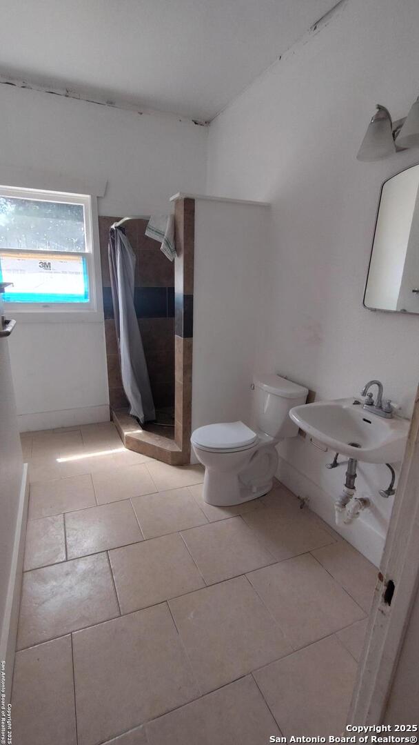 1601 Fulton Ave, San Antonio, TX 78201 - full bath featuring toilet, a stall shower, a sink, and tile patterned flooring