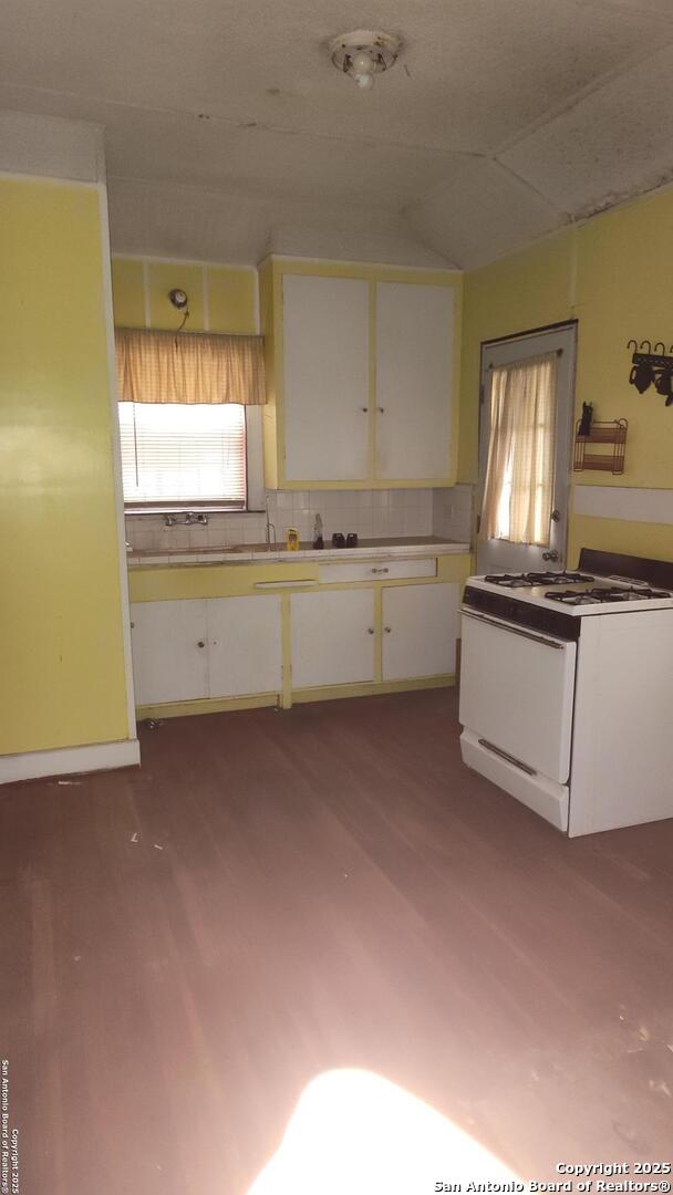1601 Fulton Ave, San Antonio, TX 78201 - kitchen featuring white gas stove, white cabinets, plenty of natural light, and wood finished floors