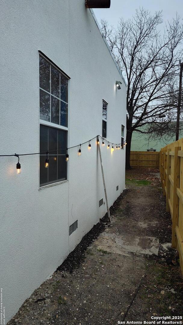 1601 Fulton Ave, San Antonio, TX 78201 - view of side of home featuring a fenced backyard, stucco siding, and crawl space