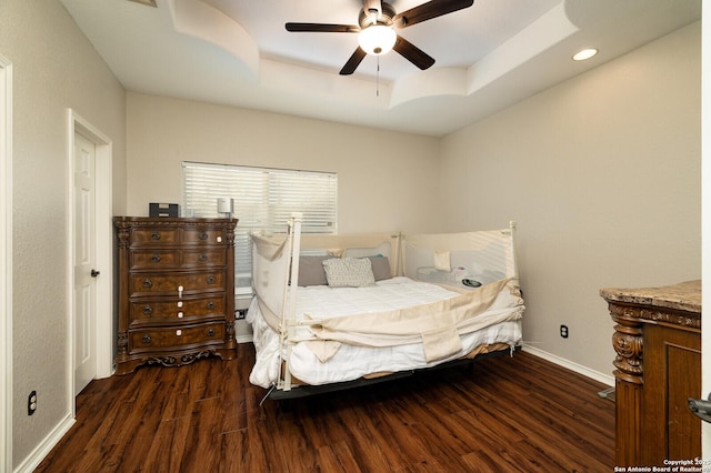 bedroom featuring dark wood-type flooring, ceiling fan, and a tray ceiling