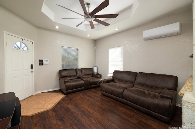 living room featuring a raised ceiling, ceiling fan, hardwood / wood-style flooring, and a wall unit AC