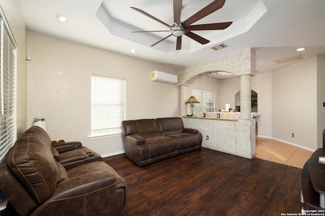 living room featuring ceiling fan, hardwood / wood-style floors, a raised ceiling, and a wall mounted AC