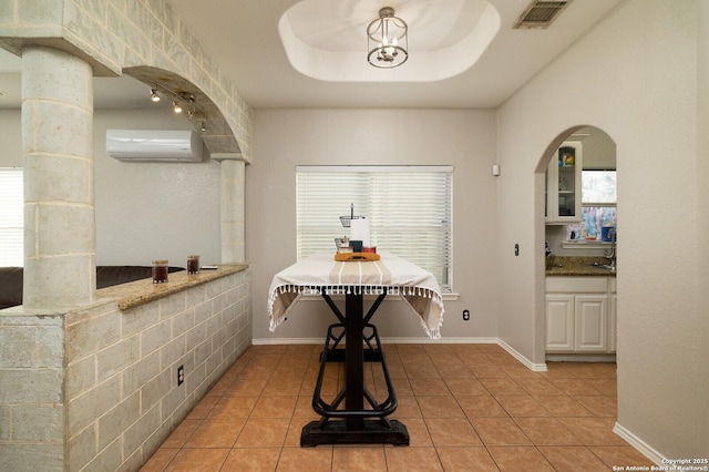 tiled dining space featuring a wall mounted air conditioner and a tray ceiling