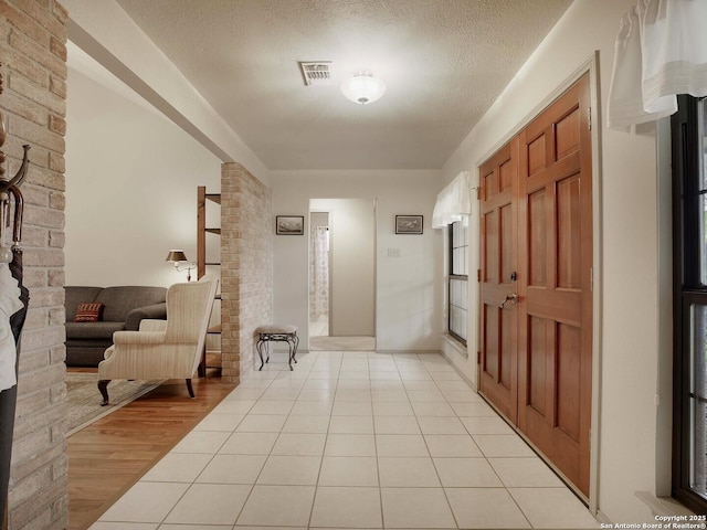 corridor featuring a textured ceiling and light tile patterned flooring