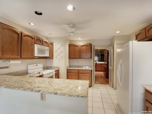 kitchen featuring kitchen peninsula, light tile patterned floors, ceiling fan, light stone counters, and white appliances