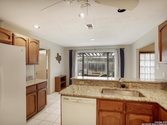 kitchen featuring light tile patterned flooring, white appliances, light stone countertops, and sink