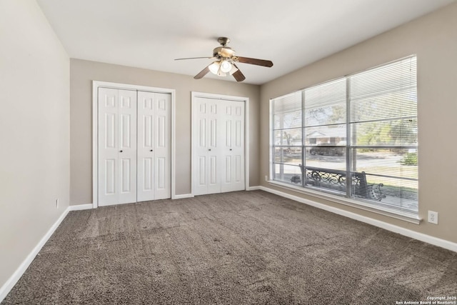 unfurnished bedroom with ceiling fan, multiple closets, and carpet