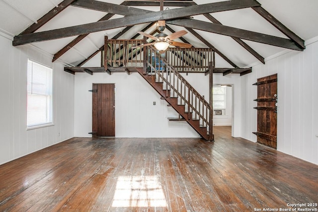 unfurnished living room with lofted ceiling with beams, dark wood-type flooring, a wealth of natural light, and ceiling fan