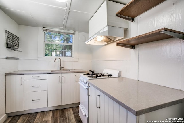 kitchen with sink, gas range gas stove, premium range hood, white cabinetry, and dark hardwood / wood-style flooring