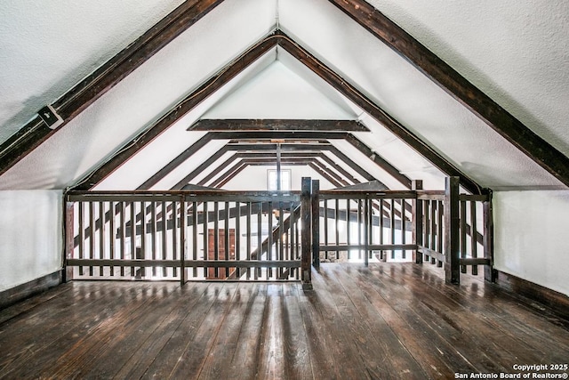 bonus room with wood-type flooring and vaulted ceiling with beams