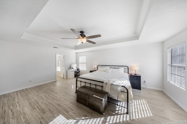 bedroom with multiple windows, a tray ceiling, a textured ceiling, and light wood-type flooring