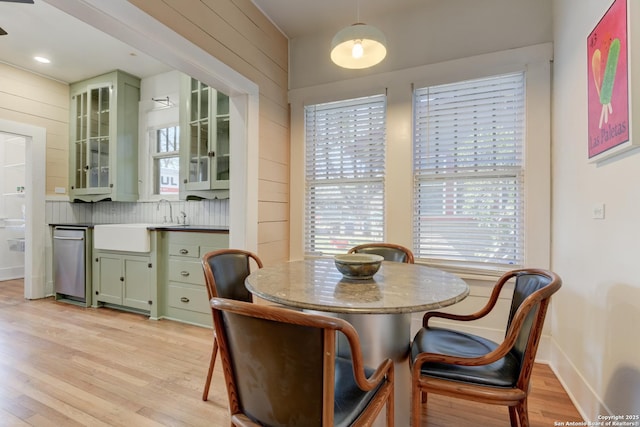 dining area with sink, light hardwood / wood-style floors, and wood walls