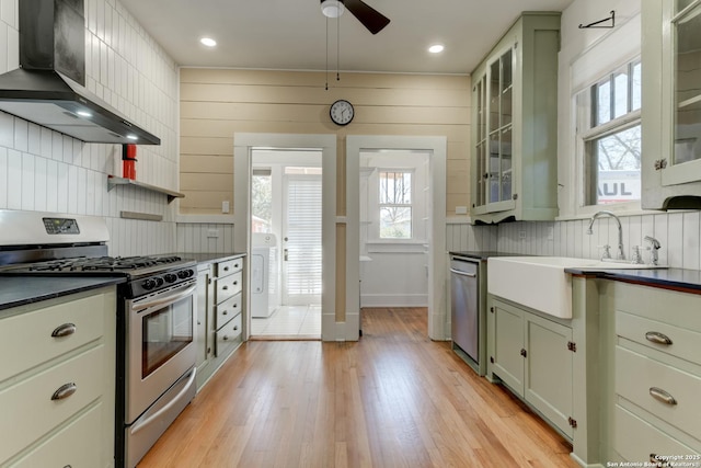 kitchen featuring sink, stainless steel appliances, tasteful backsplash, light hardwood / wood-style floors, and washer / clothes dryer