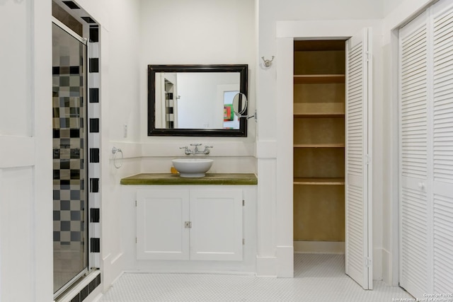 bathroom with a shower with door, vanity, and tile patterned flooring