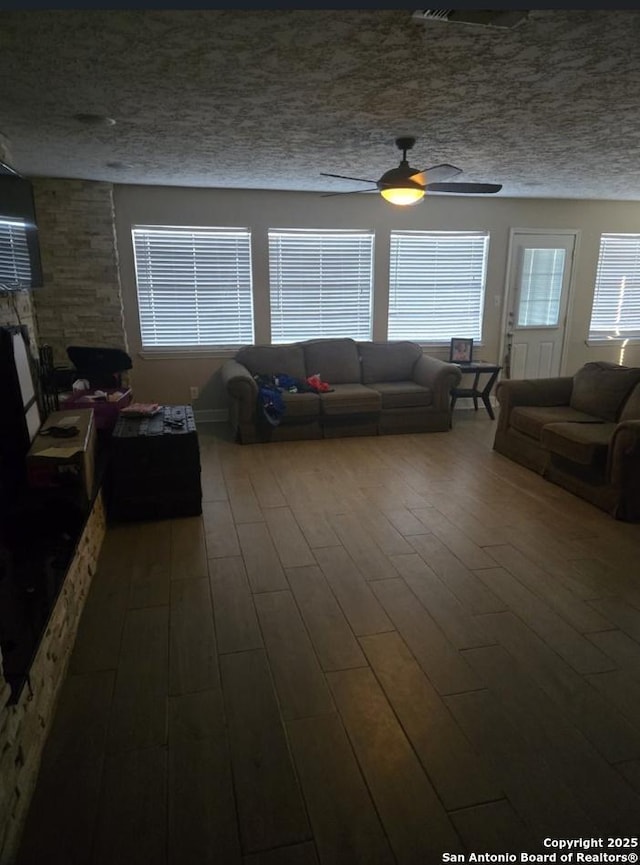 living room featuring ceiling fan, hardwood / wood-style floors, and a textured ceiling