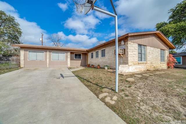 single story home featuring stone siding and fence