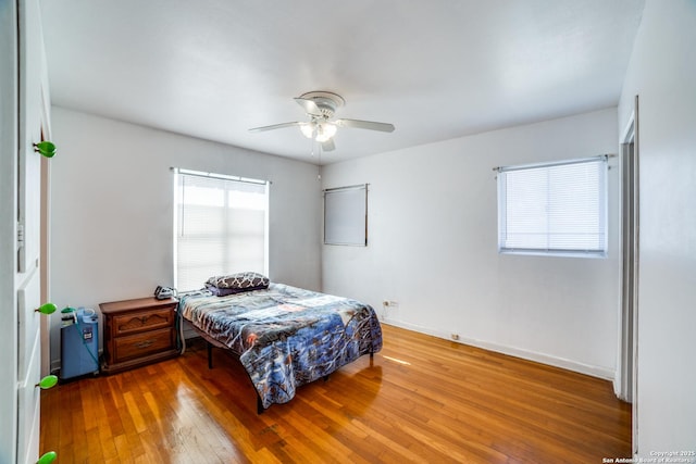 bedroom with ceiling fan, baseboards, and wood finished floors