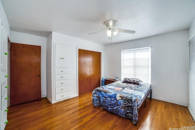 bedroom with dark wood-style floors, a closet, a ceiling fan, and baseboards