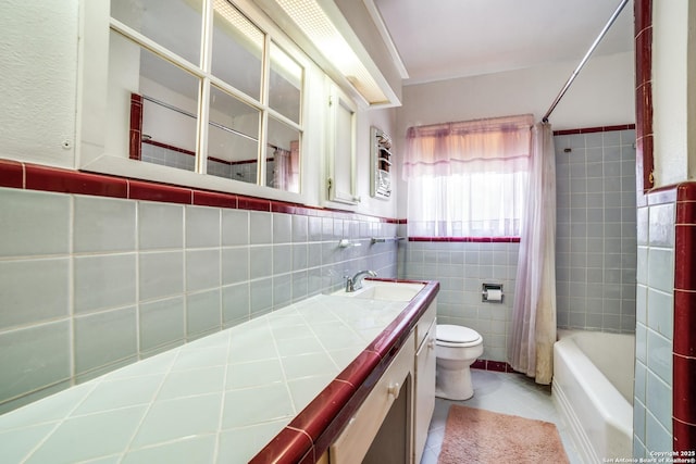 full bath featuring toilet, tile patterned floors, shower / bath combo with shower curtain, vanity, and tile walls