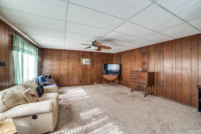 unfurnished living room featuring a ceiling fan, a wall mounted air conditioner, carpet flooring, a paneled ceiling, and wood walls