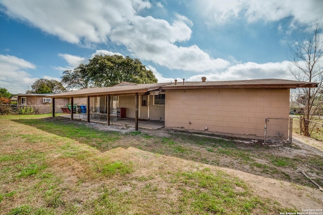 back of house featuring a yard, concrete block siding, a patio area, and fence