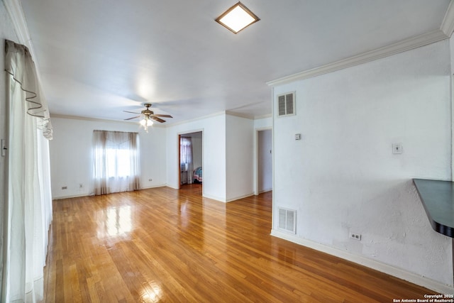 interior space featuring ornamental molding, wood finished floors, visible vents, and a ceiling fan