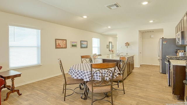 dining room featuring sink, vaulted ceiling, and light hardwood / wood-style floors