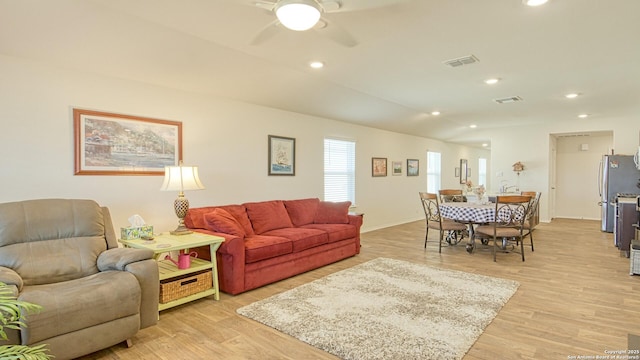 living room featuring vaulted ceiling, light hardwood / wood-style floors, and ceiling fan