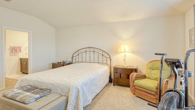 bedroom with connected bathroom, vaulted ceiling, and light carpet